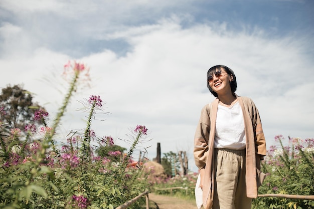 Asiatische hübsche Frau lächelt, die im Blumengarten spazieren geht