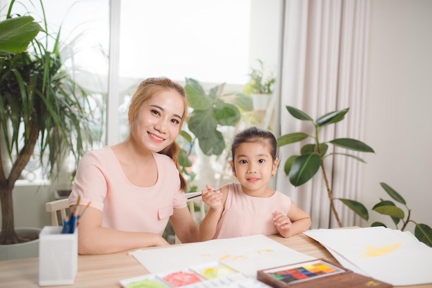 Asiatische hübsche junge mutter und ihre tochter, die zusammen die gipspuppe schmerzt