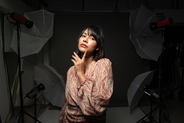 Asiatische indische Frau zeigt schönes Lächeln, glückliche Lippen, Mode-Posen im Fotostudio mit Ausrüstung