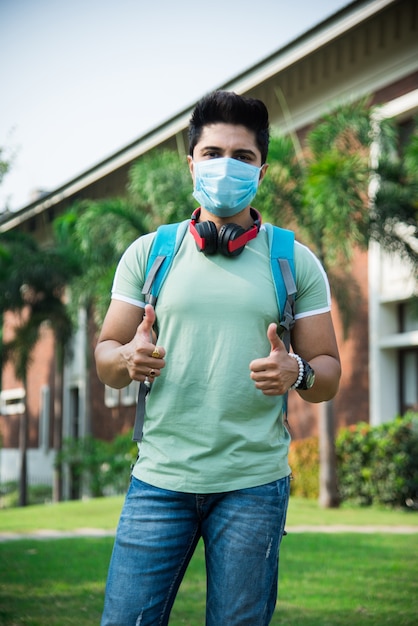 Asiatische indische Studenten tragen Gesichtsmaske und befolgen soziale Distanzierungsnormen auf dem College- oder Universitätscampus nach der Entsperrung der Corona-Pandemie, konzentrieren Sie sich auf einen Studenten