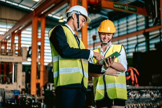 Asiatische Ingenieurin, die Bauarbeiterhelm trägt und eine Checkliste im Maschinenbereich hält?