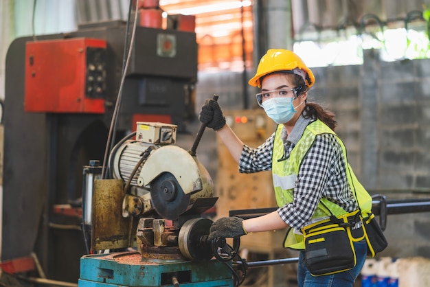 Asiatische Ingenieurinnen mit Hygienemaske schützen mit Helmsicherheit in der Fabrik Industrial