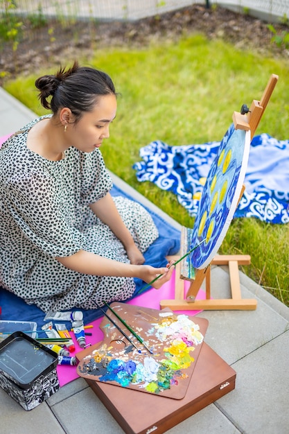 Asiatische junge Frau, die Bild in der Heimterrasse malt