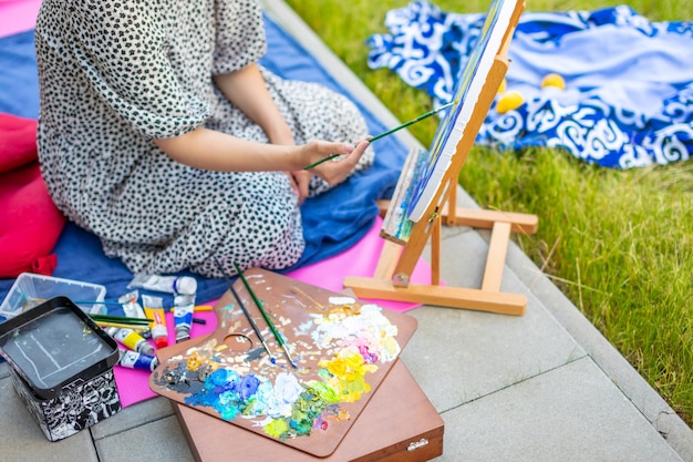 Asiatische junge Frau, die Bild in der Heimterrasse malt