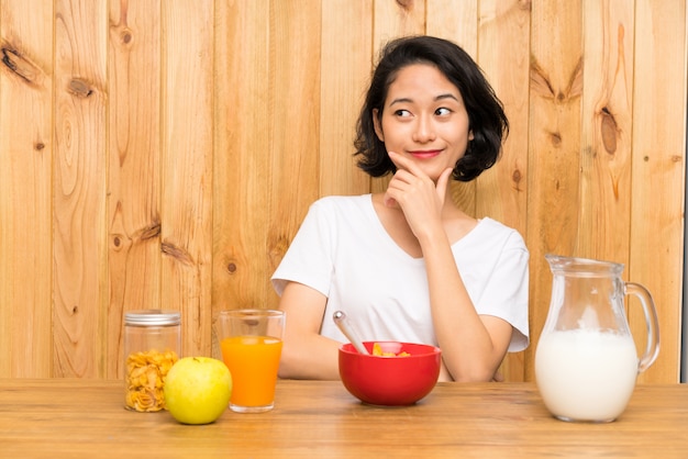 Asiatische junge Frau, die Frühstücksmilch denkt eine Idee hat