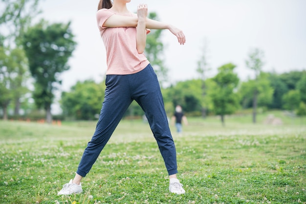 Asiatische junge Frau, die im Park ausübt