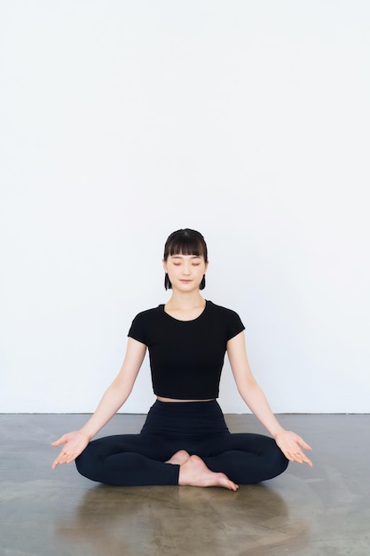 Asiatische junge Frau, die Mantra-Meditation in Yoga-Pose macht