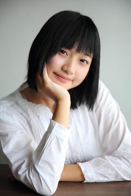 Asiatische junge Frau, die Porträt im Café des Cafés denkt und schaut