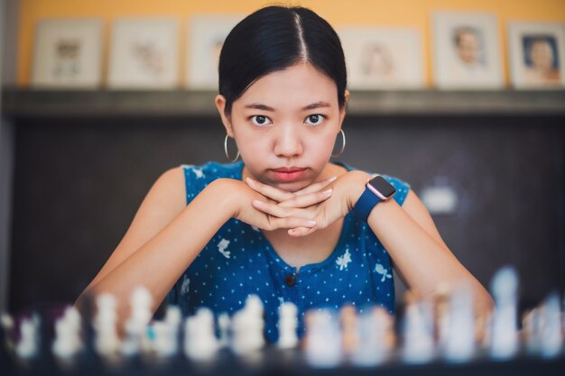 Asiatische junge Frau, die zu Hause Schach spielt