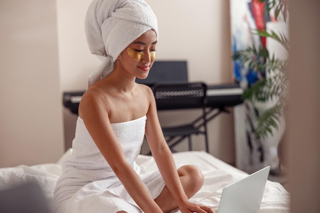 Asiatische junge Frau mit Laptop nach der Dusche zu Hause