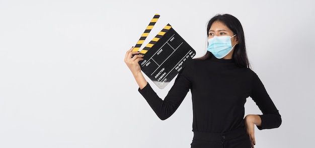 Asiatische junge Frau trägt Gesichtsmaske oder medizinische Maske und hält schwarzes Klappbrett