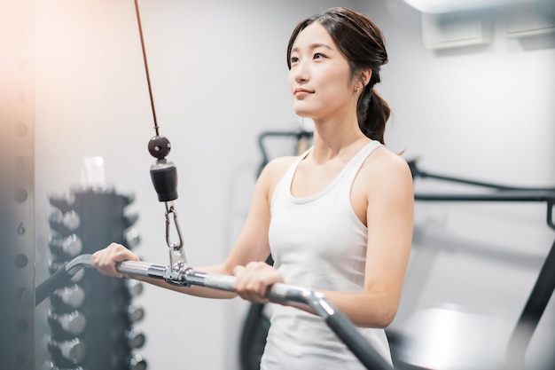 Asiatische junge Frau trainiert im Fitnessstudio