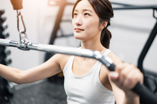 Asiatische junge Frau trainiert im Fitnessstudio