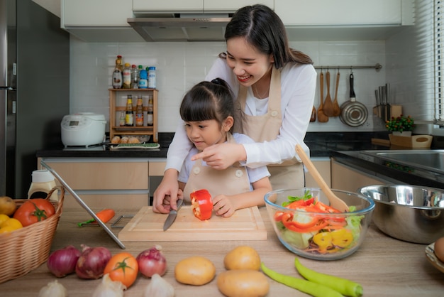 Asiatische junge Frau und ihre Tochter, die Salat für das Mittagessen kocht.