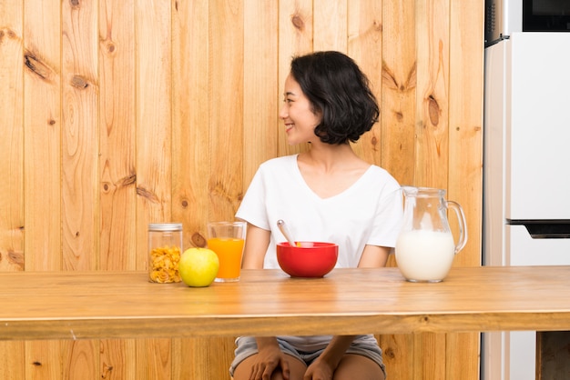 Asiatische junge Frau, welche die Frühstücksmilch schaut zur Seite hat