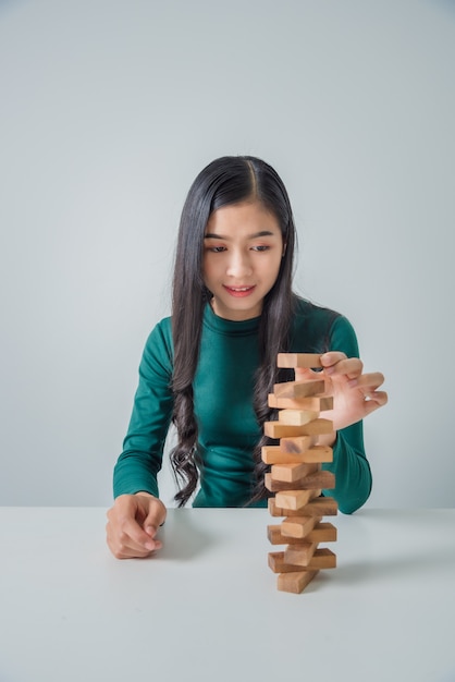 Asiatische junge Geschäftsfrau, die mit Holzklötzen spielt