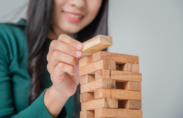 Asiatische junge Geschäftsfrau, die mit Holzklötzen spielt