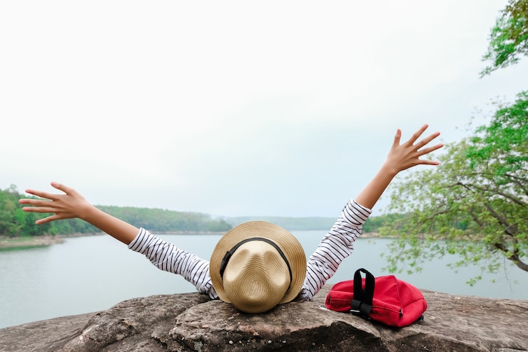 Foto asiatische junge mädchen mit dem hellen rucksack, der in der natur während der ferien genießt.