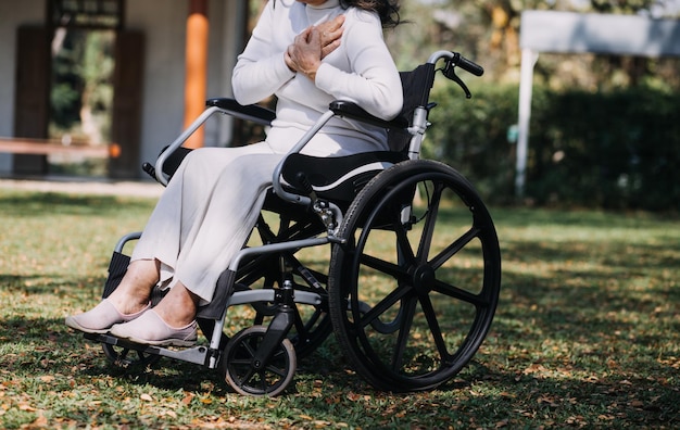 Asiatische junge Pflegekraft unterstützt ältere ältere Männer, die im Freien spazieren gehen Fachärztin hilft und kümmert sich um ältere Patienten, die im öffentlichen Park im Pflegeheim Physiotherapie machen