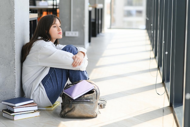 Asiatische junge Studentin, die allein mit dem traurigen Gefühl an der Schule sitzt