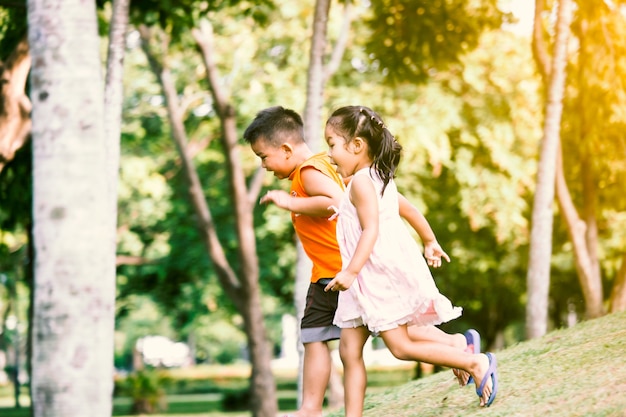 Asiatische Kinder, die Spaß haben, im Park im Weinlesefarbton zusammen zu laufen und zu spielen