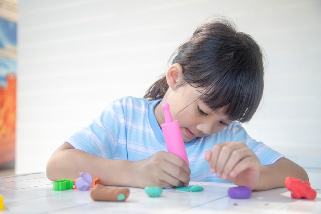 Asiatische Kinder spielen mit Tonformformen und lernen spielerisch