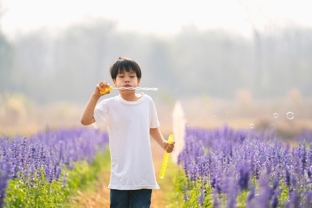 Asiatische Kinderjungen genießen das Blasen einer Seifenblase in der Gartenblume