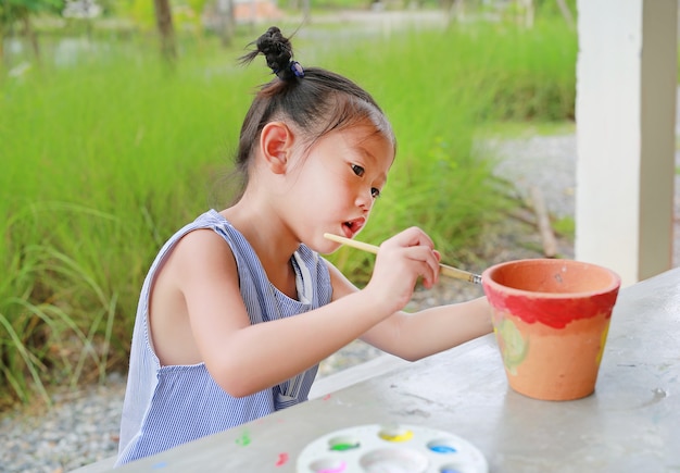 Asiatische Kindermädchenfarbe auf Töpferwarenteller.