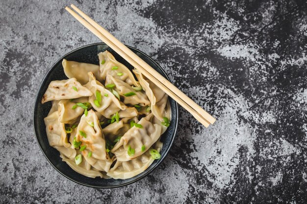 Asiatische Knödel in der Schüssel mit Essstäbchen Draufsicht