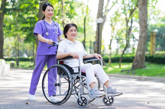 Asiatische Krankenschwester, die sich um eine Patientin mittleren Alters im Park kümmert