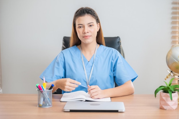 Asiatische Krankenschwester sitzt im Büro