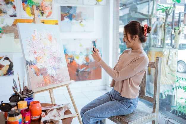 Asiatische Künstlerin fotografiert ihr eigenes Gemälde mit Smartphone