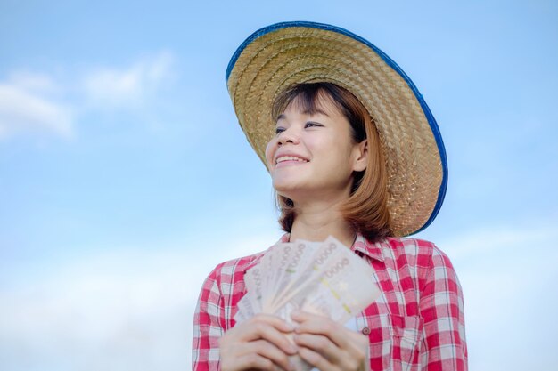 Asiatische Landwirtin im Reisfeld, die Geld hält