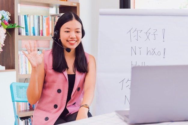 Asiatische Lehrerin, die fern zu Hause mit Online-Technologie-Laptop unterrichtet.