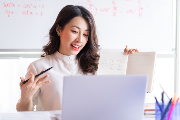 Asiatische Lehrerin, die online zu Hause unterrichtet
