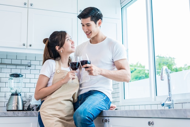 Asiatische Liebhaber oder Paare, die zu Hause Wein im Küchenraum trinken