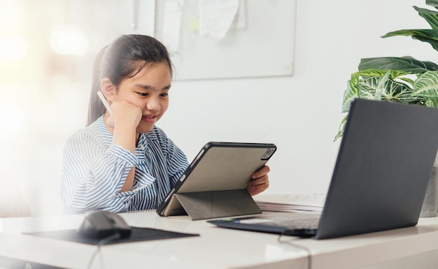 Asiatische Mädchen, die Laptop-Tablets verwenden und über ein Online-E-Learning-System lernen. Neue Normalität.Covid-19 Coronavirus.Soziale Distanzierung.Bleiben Sie zu Hause