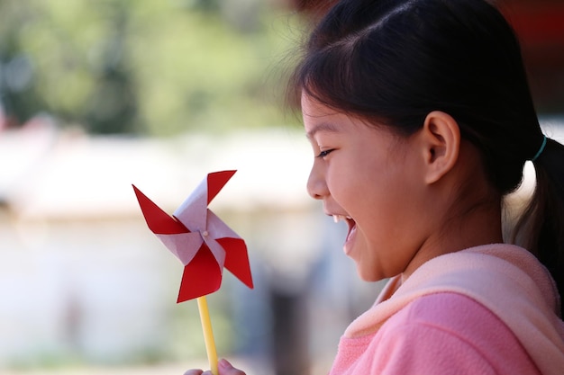 Asiatische Mädchen spielen Windmühlenspielzeug und freuen sich sehr über Design in Ihrem Arbeitskonzept.