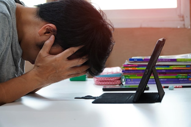 Asiatische Männer mit Kopfschmerzen von der Arbeit zu Hause Mann fühlt sich müde, gelangweilt und schläfrig auf dem Tisch sitzend