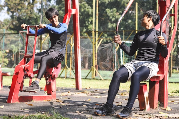 Asiatische Männer spielen im Park an Trainingsgeräten