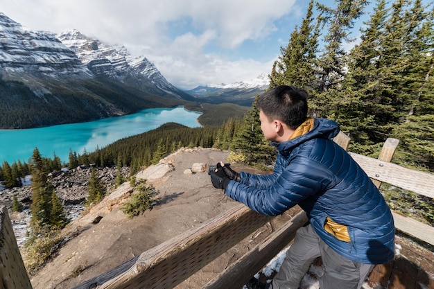 Asiatische männliche Touristen stehen und genießen den Blick auf den Peyto Lake am Aussichtspunkt im Banff Nationalpark Kanada