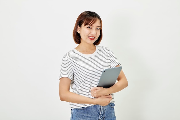 Asiatische Mitarbeiterin eines Unternehmens lächelt und hält ein digitales Tablet im Stehen