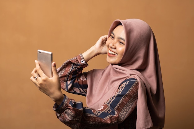 Asiatische Muslima machen Selfie auf ihrem Handy