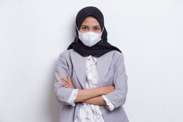 Asiatische muslimische frau, die eine medizinische gesichtsmaske trägt, um das koronavirus covid19 zu schützen, das auf weiß posiert