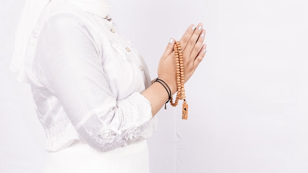 Asiatische muslimische Frau, die Gebetsperlen trägt, die Gäste oder Ied Fitr-Gruß im weißen Raum begrüßen