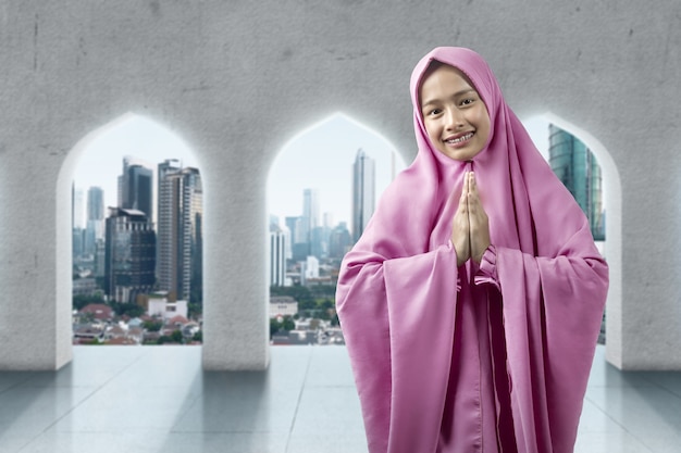 Asiatische muslimische Frau im Schleier mit Begrüßungsgeste auf der Moschee