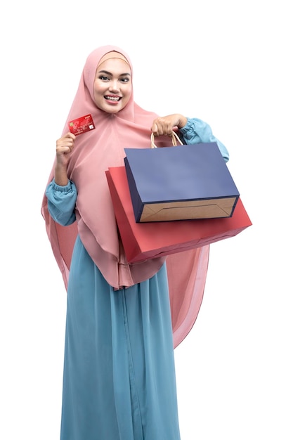 Asiatische muslimische Frau im Schleier mit Kreditkarte und Einkaufstaschen