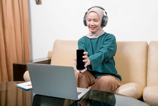 Asiatische muslimische Geschäftsfrau, die einen Laptop verwendet, der von zu Hause aus arbeitet. Grippeerkrankung Coronavirus vorbeugen