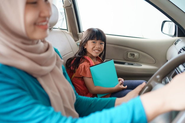 Asiatische muslimische Mutter, die ihre Tochter morgens mit dem Auto zur Schule bringt. glücklicher Schüler, der wieder zur Schule geht