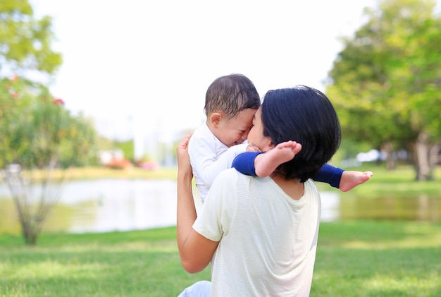 Asiatische Mutter der glücklichen Familie und ihr Sohn, die im Naturgarten spielt